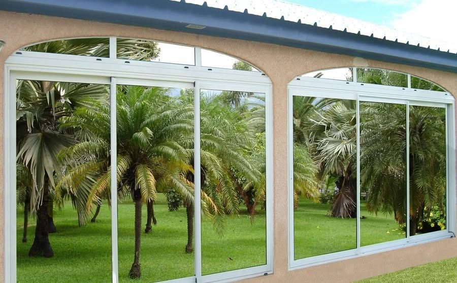 Deux baies coulissantes aluminium blanc sous arches, ouvertes sur un jardin de palmiers