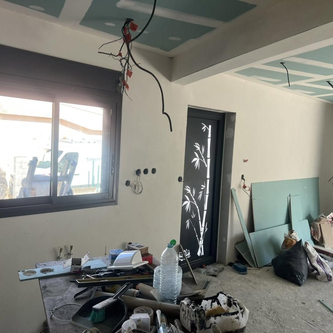 Pièce en chantier avec fenêtre coulissante noire et porte décorée de bambous découpés