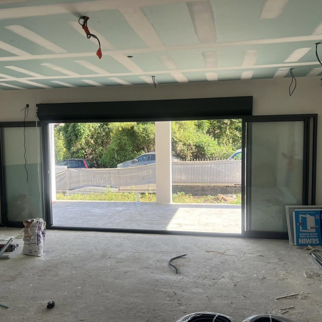 Baie coulissante noire avec coffre de volet roulant, maison en construction
